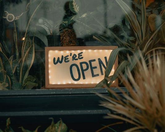 A rustic 'We’re Open' sign welcoming visitors to Primrose Farm Shop & Café in Marnhull.